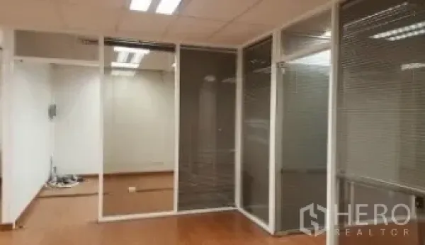 Office Space for rent in Bang Rak, Bangkok - Bangkok office interior with glass-partitioned rooms, blinds, wood flooring, and ceiling lights.