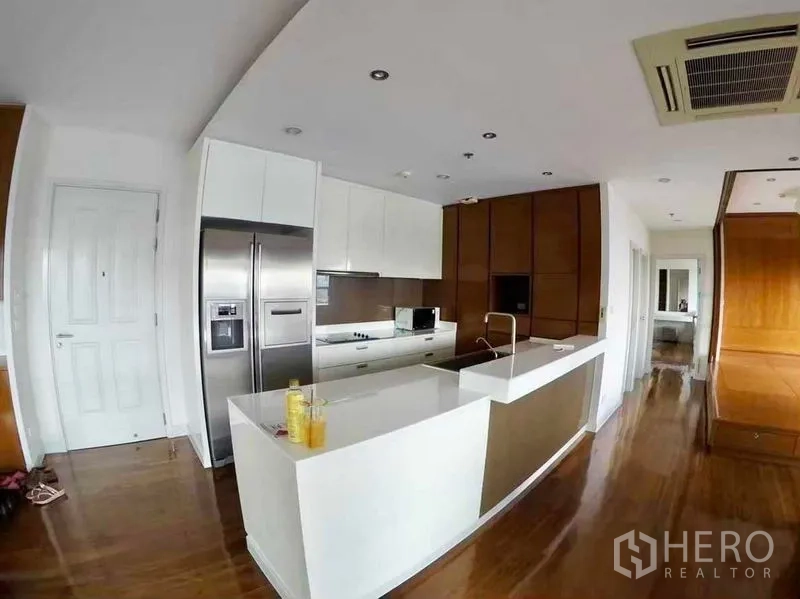 Condominium for rent or sale in Khlong San, Bangkok - Modern Bangkok condo kitchen with white island, stainless double-door fridge and wooden floors.
