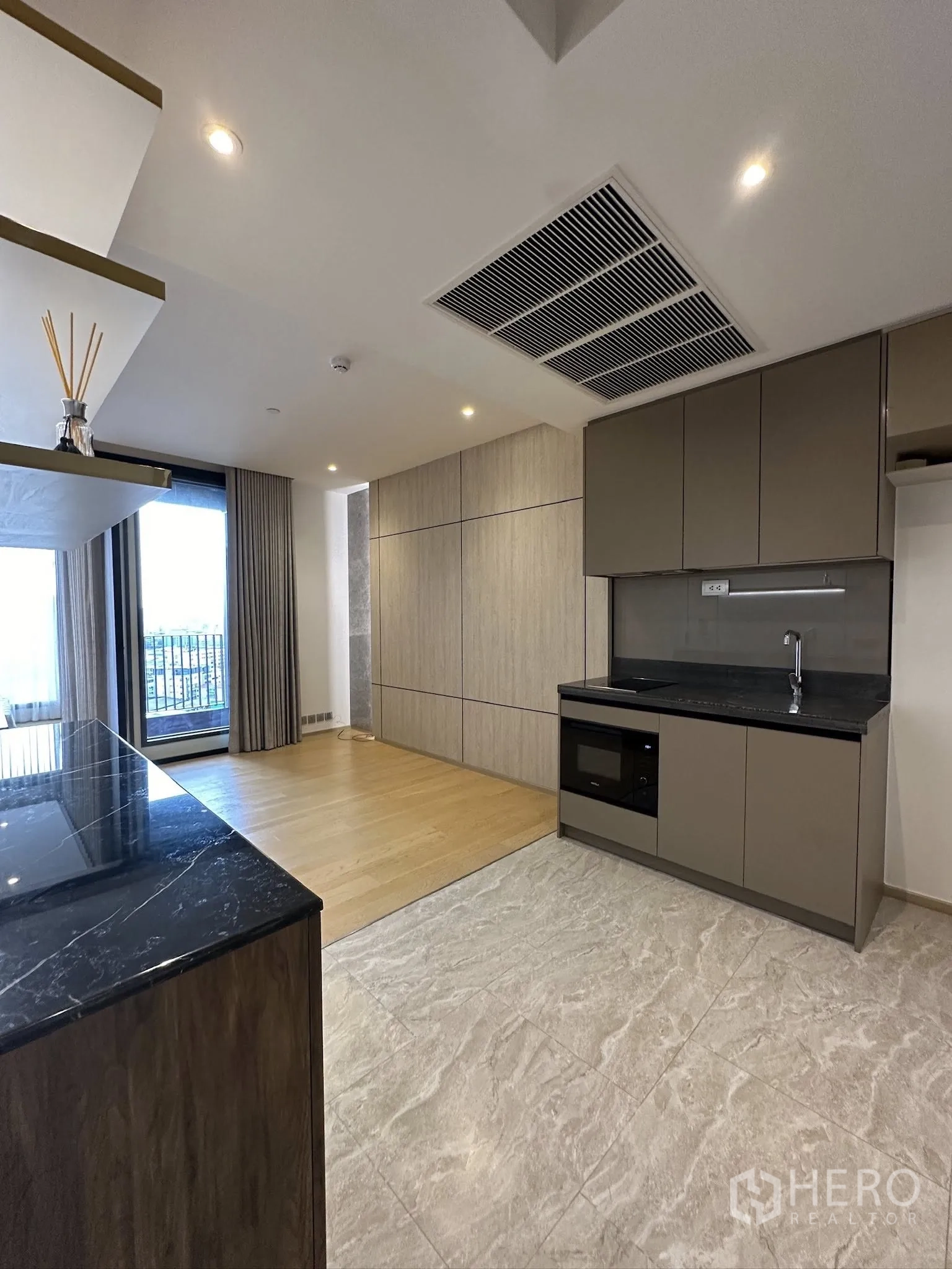 คอนโด for sale in Din Daeng, Bangkok - พื้นที่ครัวและนั่งเล่นโอเพ่นแพลน ท็อปหินสีดำ พื้นไม้ และหน้าต่างระเบียง