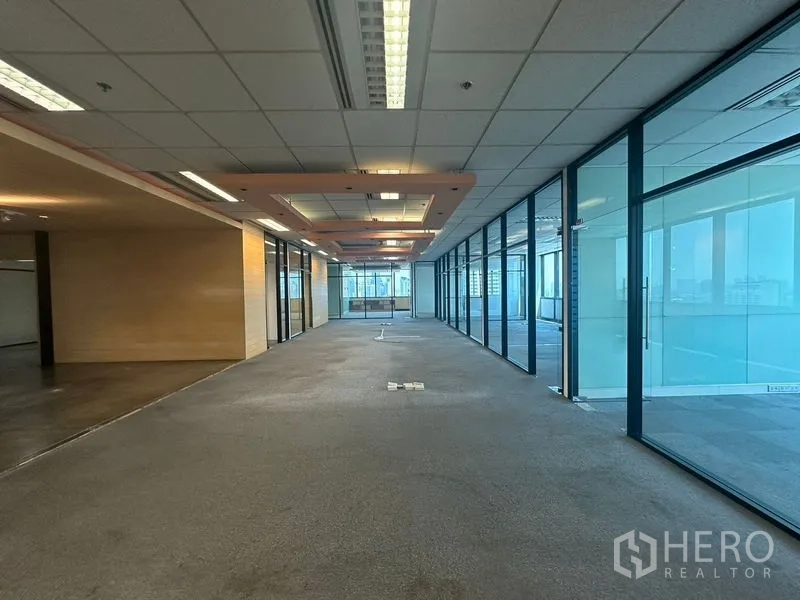 Office Space for rent in Khlong Toei, Bangkok - Long corridor-style office zone with glass walls on one side and ceiling feature panels.