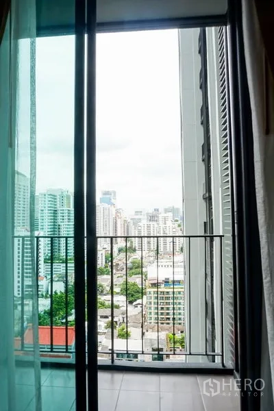 Condominium for sale in Watthana, Bangkok - Sliding glass door opening to a balcony overlooking Bangkok cityscape.