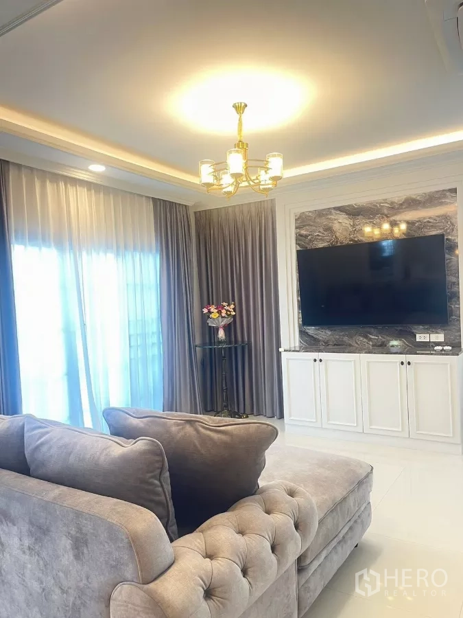 Detached House for rent in Bang Phli, Samut Prakan - Living area with tufted sofa facing TV feature wall with marble accents.