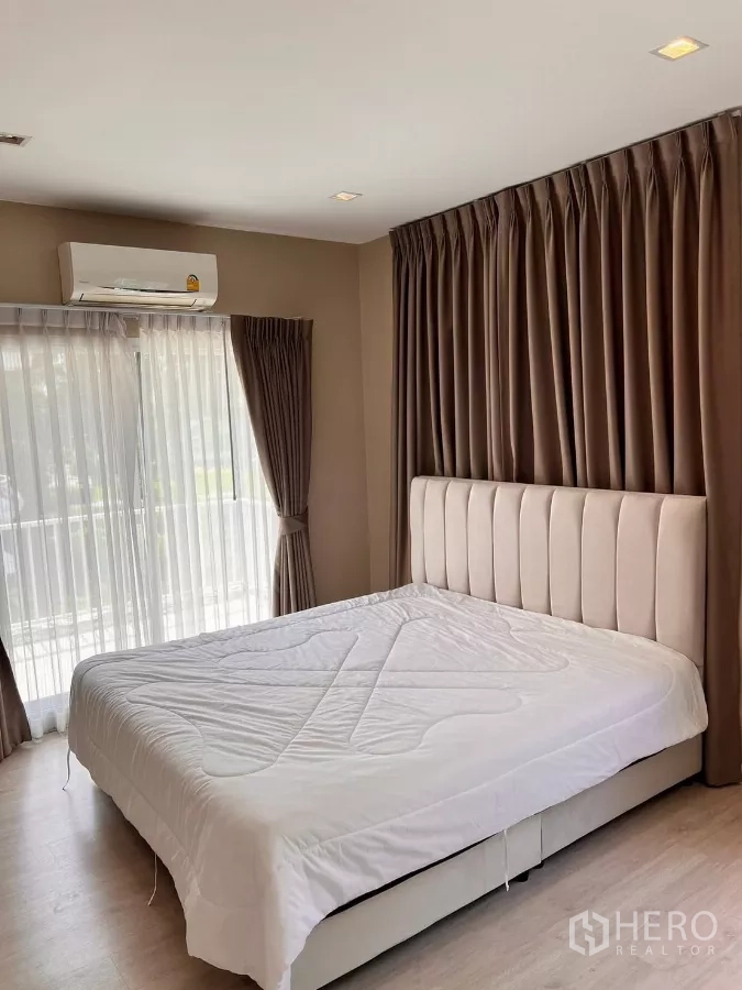 บ้าน ให้เช่าในLat Krabang, Bangkok - ห้องนอนใหญ่มีประตูกระจกบานเลื่อนไปสู่ระเบียงและผ้าม่านทึบ