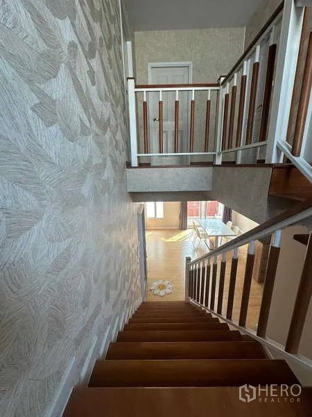 บ้าน ให้เช่า - มุมมองจากชั้นบนเห็นบันไดไม้และผนังลายวอลล์เปเปอร์