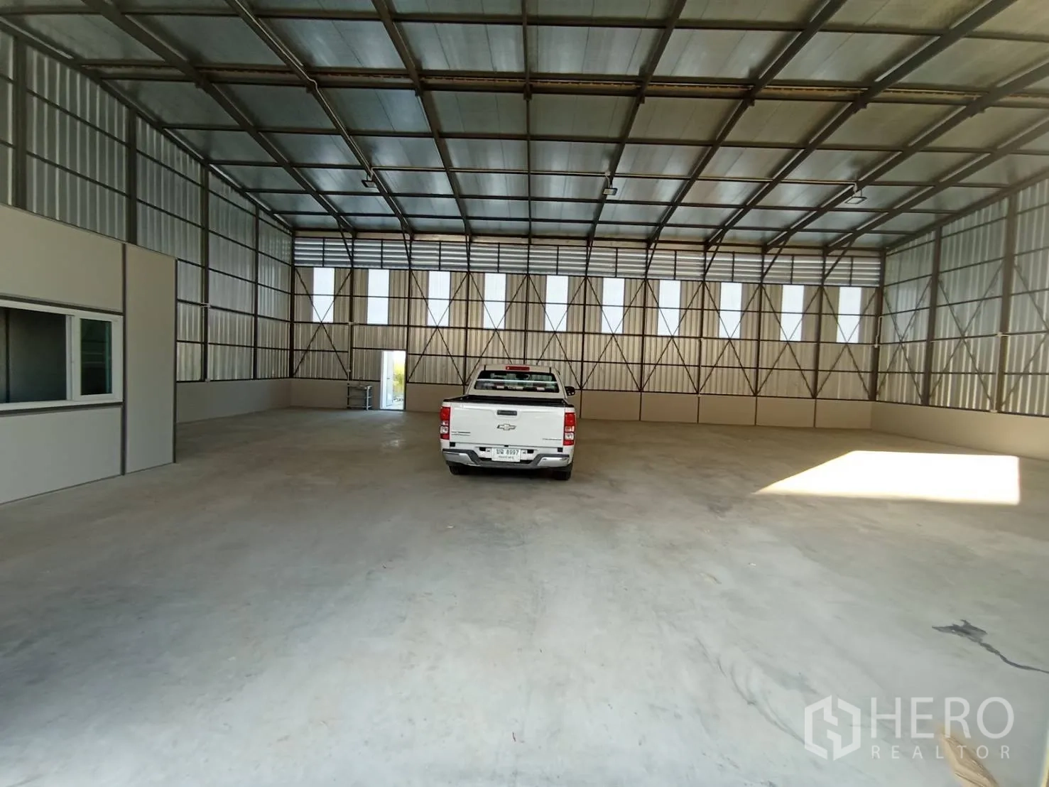 Warehouse for rent in Mueang Samut Prakan, Samut Prakan - Open warehouse space with high roof, concrete floor, and a pickup truck parked inside.