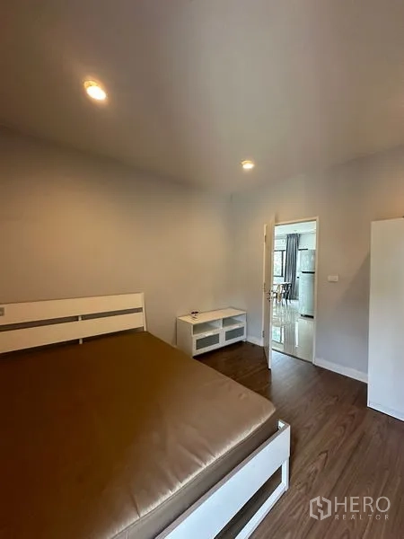 บ้าน ให้เช่าในLam Luk Ka, Pathum Thani - ห้องนอนพื้นไม้ เตียงนอนและชั้นวางทีวี