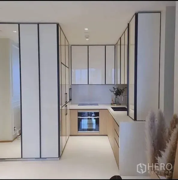 คอนโด ขายในKhlong Toei, Bangkok - ครัวรูปตัว U โทนขาว ตู้บิลท์อิน เตาอบ และเตาอินดักชัน