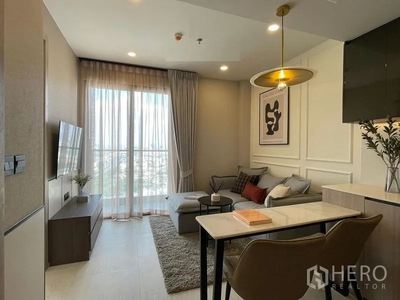 公寓 出租在Pathum Wan, Bangkok - 客厅配阳台式落地窗，转角沙发与对面电视。