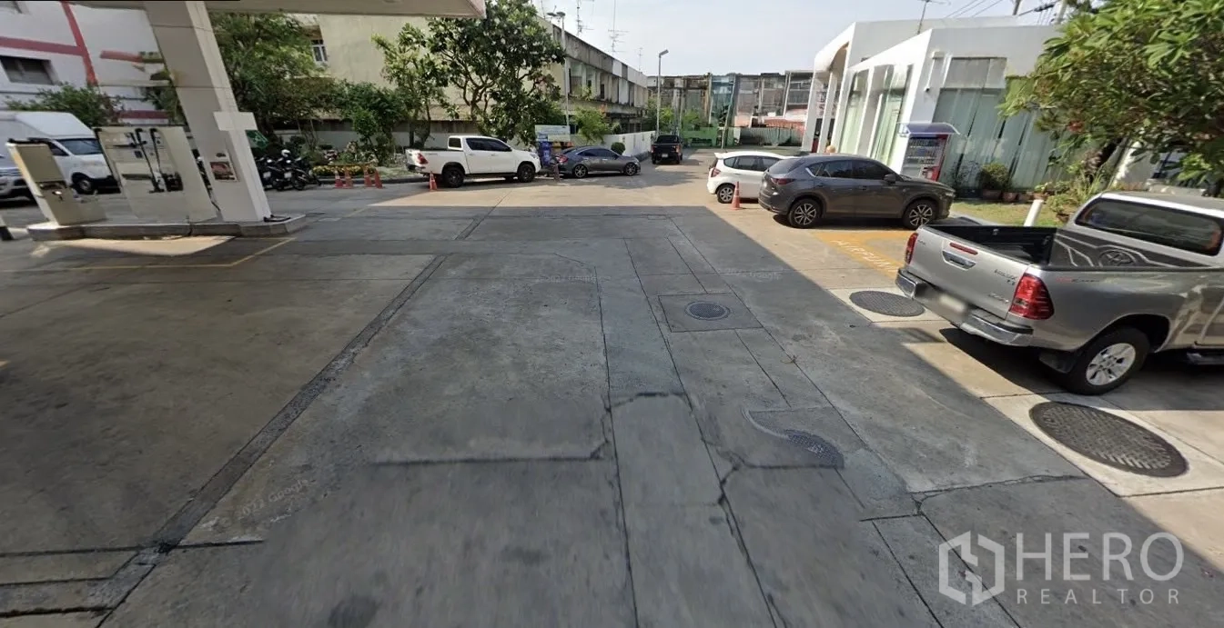 Land for sale in Phasi Charoen, Bangkok - Concrete driveway and parking area next to commercial buildings providing site access.