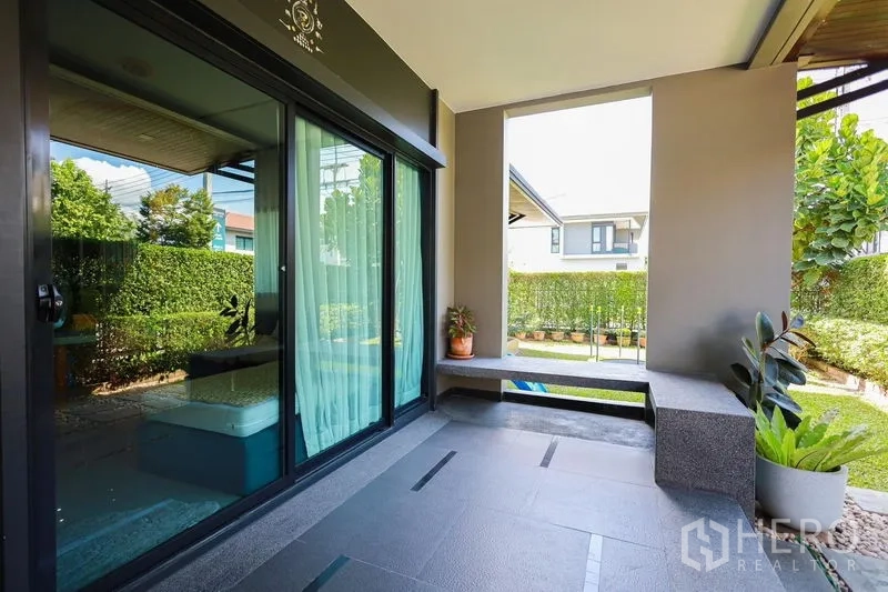 Detached House for rent or sale in Lam Luk Ka, Pathum Thani - Covered terrace facing the garden with sliding doors and built-in seating.