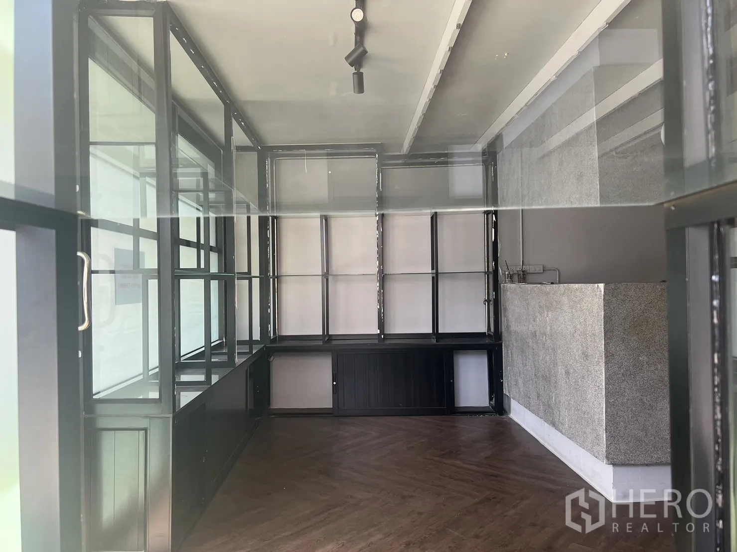 零售空间 出租在Watthana, Bangkok - 透过橱窗可见室内玻璃展示架、石材吧台和人字拼地板