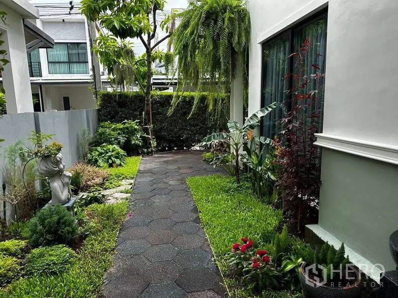 独立式住宅 出租在Prawet, Bangkok - 景观花园小径，繁茂植物与装饰雕像。