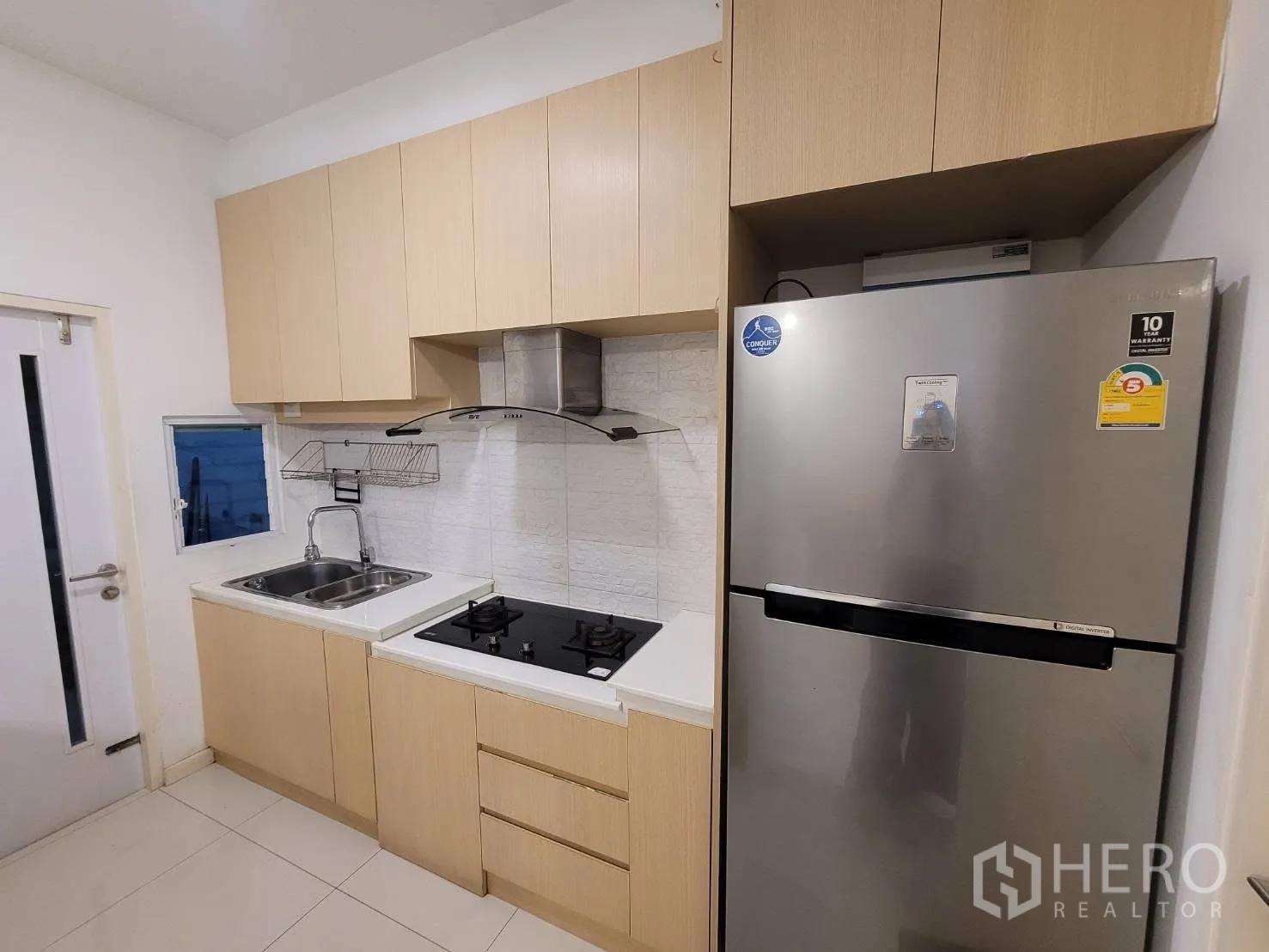 联排别墅 出租在Prawet, Bangkok - 紧凑厨房，双水槽、燃气灶、烟机与不锈钢冰箱。