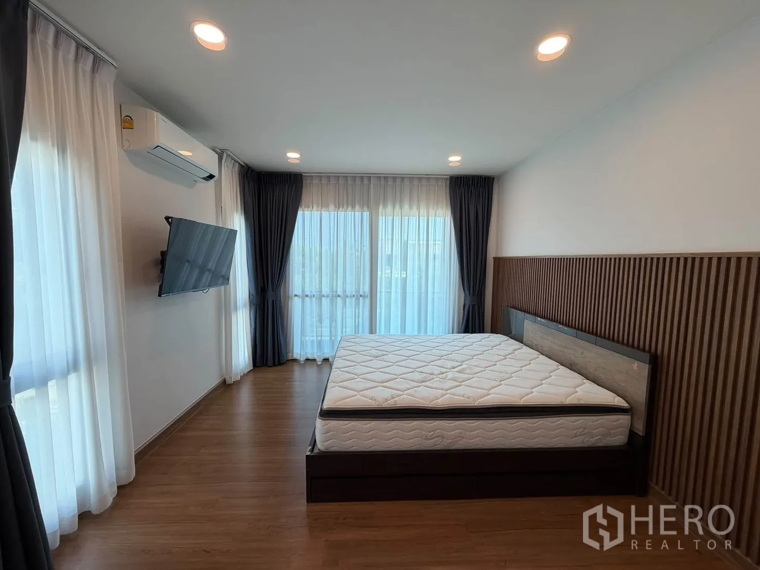 บ้านเดี่ยว for rent in Bang Phli, Samut Prakan - มุมห้องนอนหลักพร้อมทีวีติดผนังและหน้าต่างมุมกว้าง.