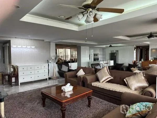 Condominium for sale in Chatuchak, Bangkok - Spacious living room with sofas, ceiling fan and open-plan kitchen beyond.