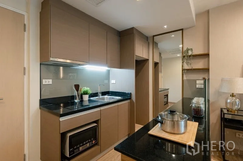 公寓 出售 - 现代厨房，黑色花岗岩台面、水槽与内置柜体。