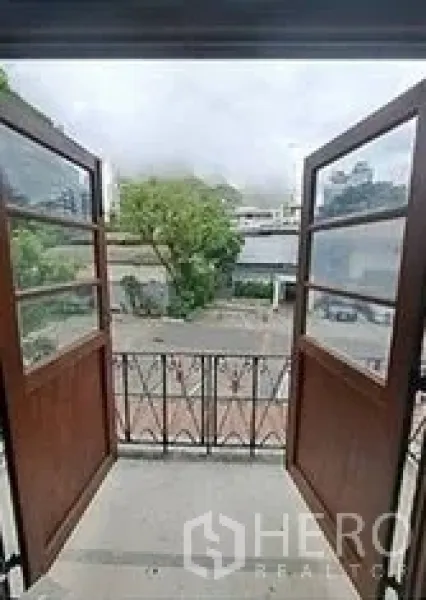 零售空间 出租在Bangkok - 木质双开门通向小阳台，可眺望曼谷城市街景。