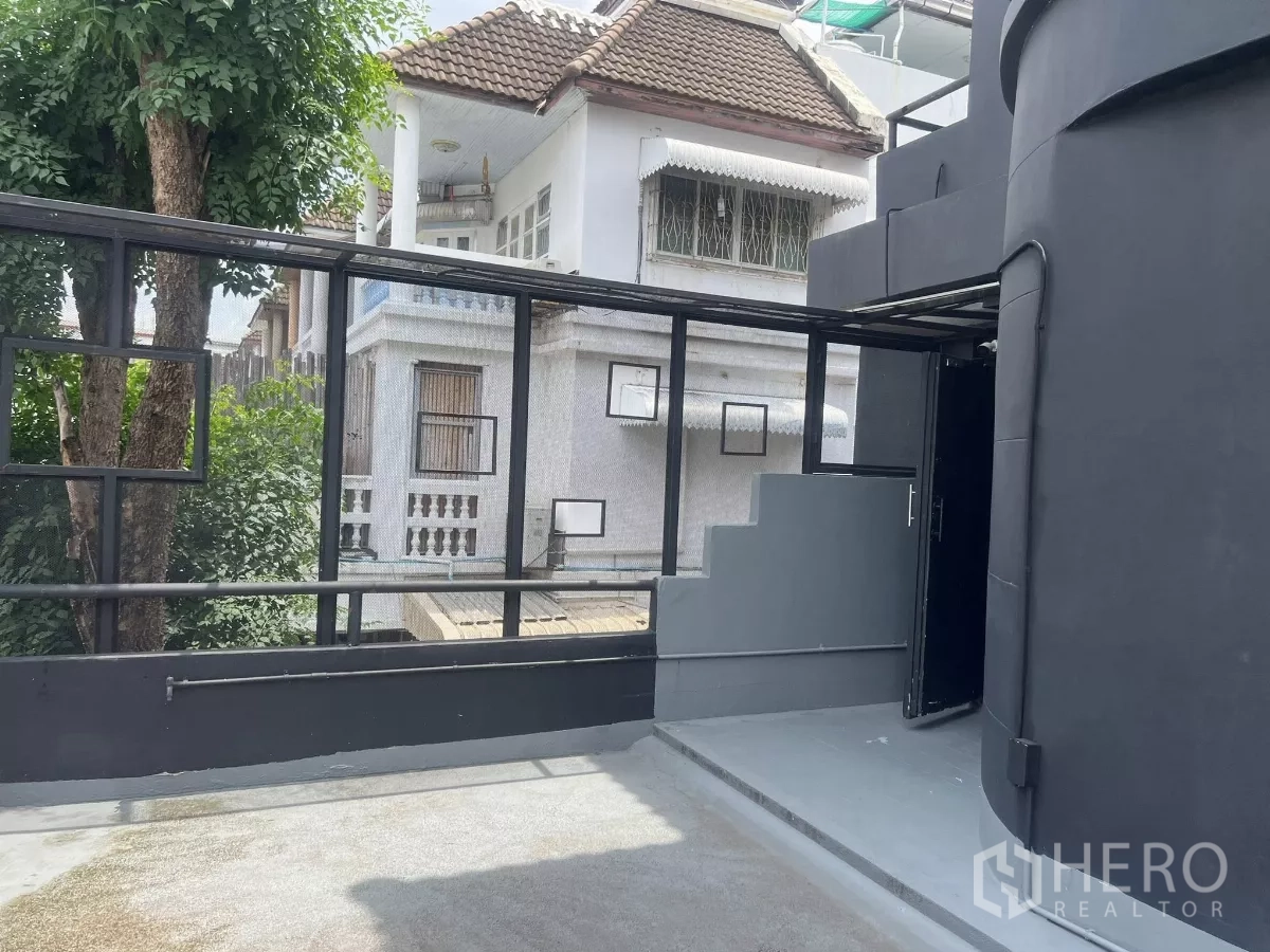 Home Office for rent in Wang Thonglang, Bangkok - Rooftop terrace with metal railing and steps overlooking neighboring houses.