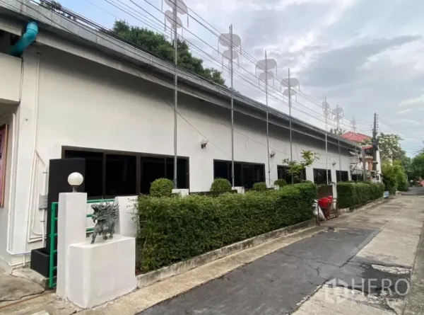 工厂 出租在Prawet, Bangkok - 工厂侧立面，整排窗户与绿篱围合的前院