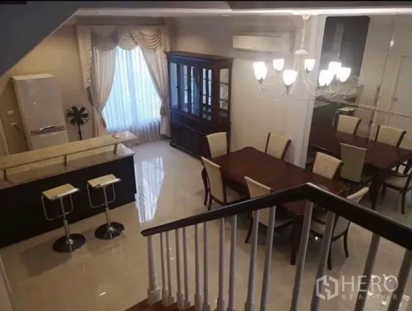 Detached House for rent in Wang Thonglang, Bangkok - Open-plan dining area with chandelier and glossy floors viewed from the staircase.