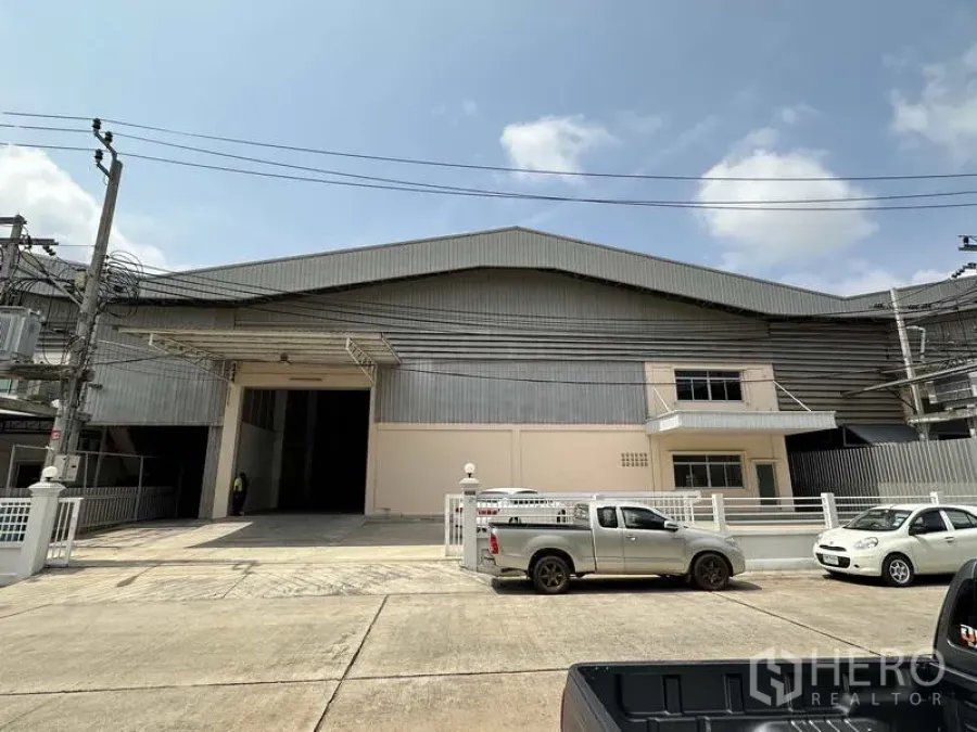 工厂 出租在Samut Prakan - 工厂正立面，宽大装卸入口、围栏与混凝土前院。