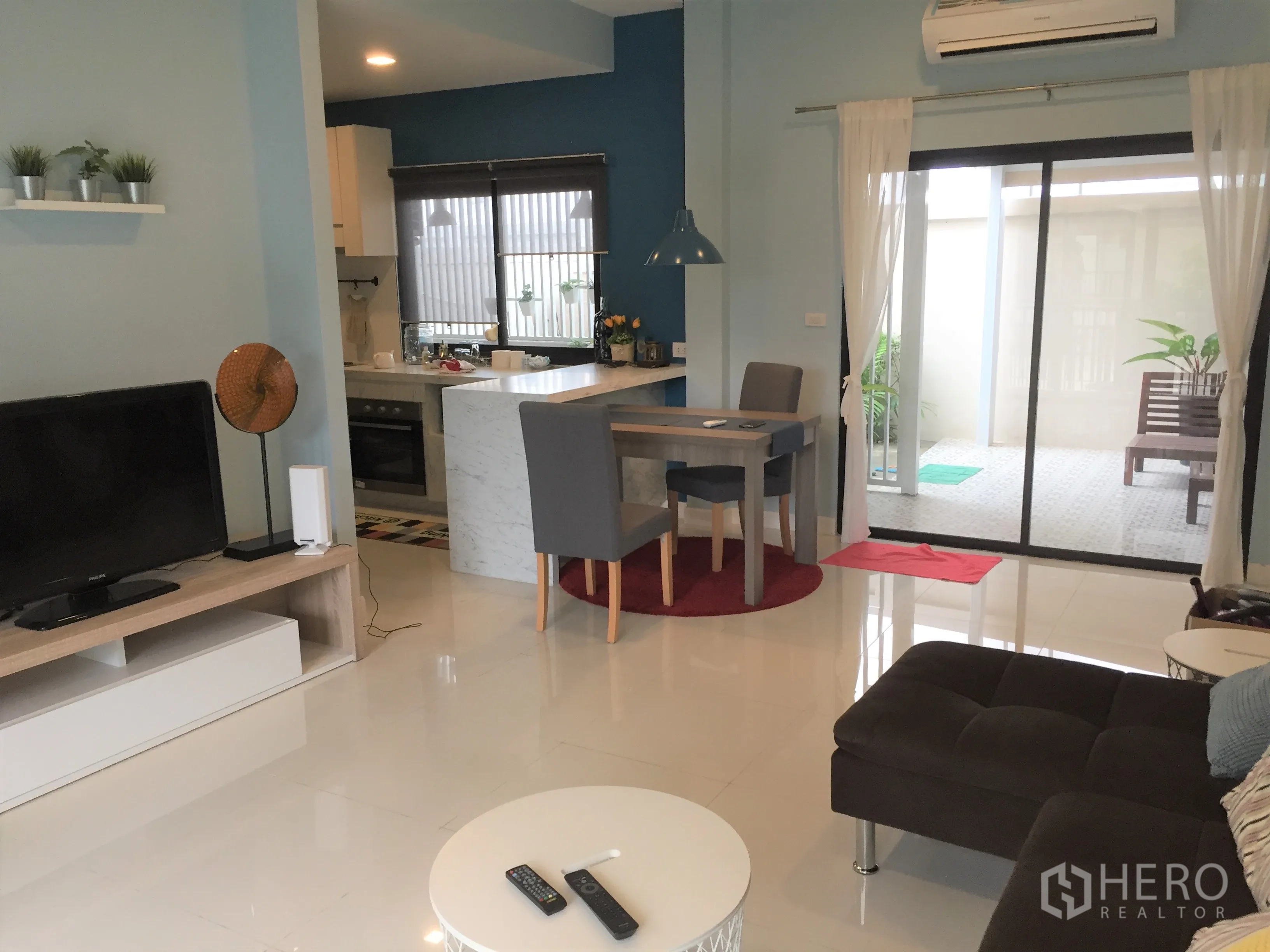 Townhouse for rent in Saphan Sung, Bangkok - Open-plan living and dining with breakfast bar, TV unit and sliding glass door to patio.