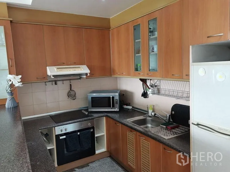 公寓 出租在Khlong Toei, Bangkok - 独立厨房，木质橱柜、炉灶、烤箱、微波炉与冰箱齐全。