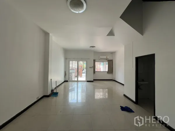 Townhouse for rent in Khlong Toei, Bangkok - Bright tiled ground-floor living area with sliding glass doors opening to the front patio.