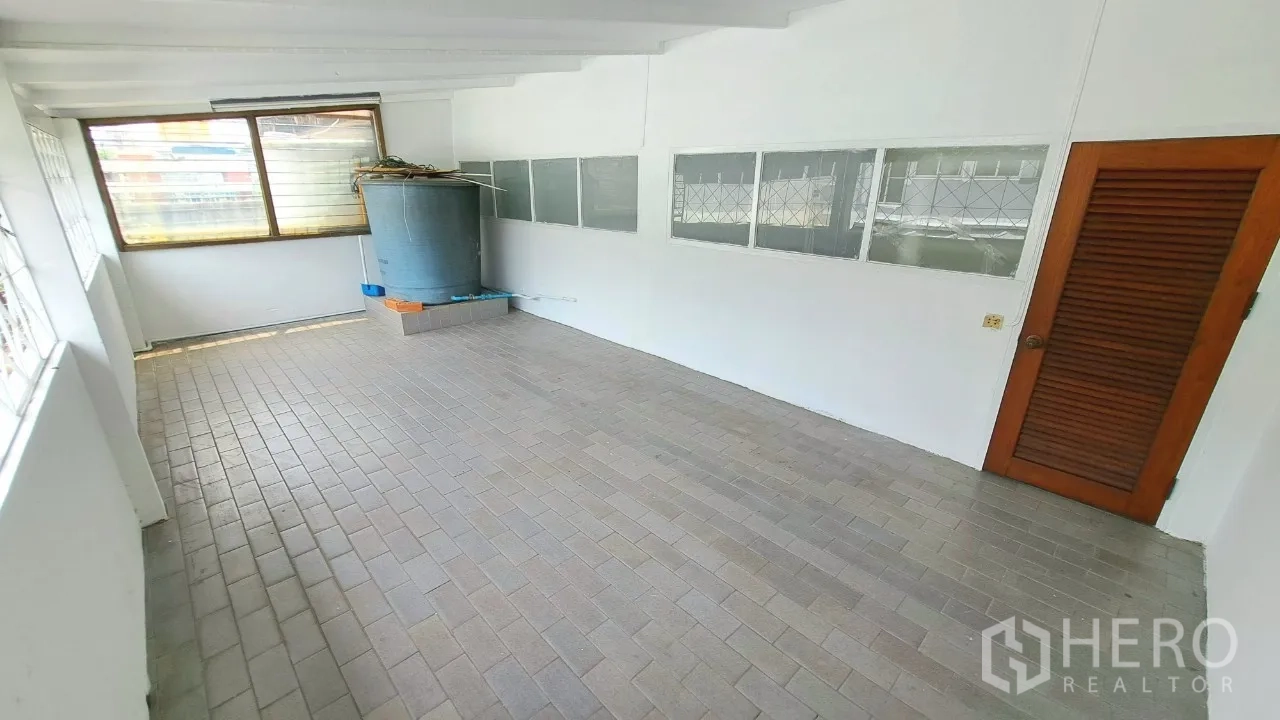 Townhouse for rent in Watthana, Bangkok - Covered utility room with brick flooring and a large water tank.