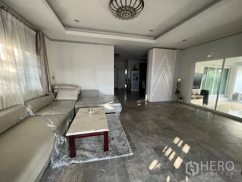 บ้าน ขายในLat Krabang, Bangkok - ห้องนั่งเล่นพร้อมโซฟาเข้ามุม โต๊ะกลาง และประตูกระจกสไลด์