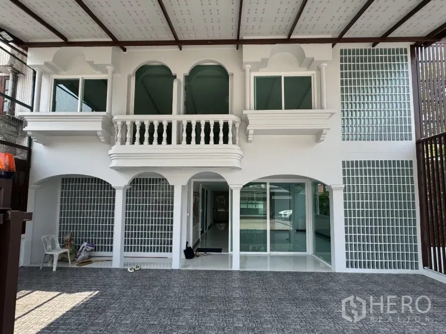 Townhouse for sale in Bueng Kum, Bangkok - Front facade of renovated white townhouse with balcony, arches and covered parking.