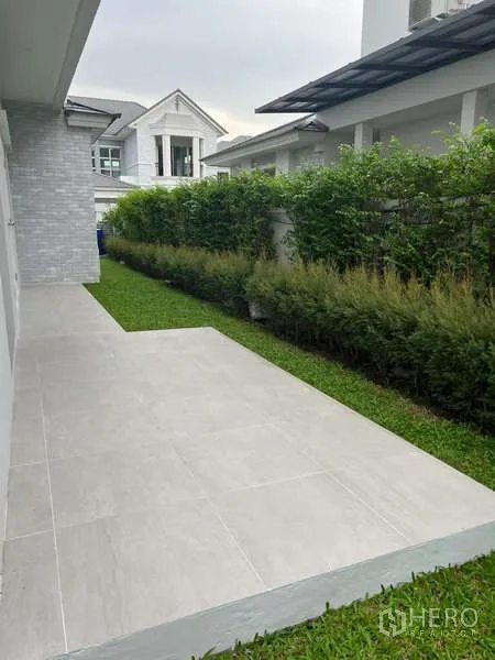 บ้าน ให้เช่าหรือขายในLat Krabang, Bangkok - ลานข้างบ้านปูพื้นกระเบื้อง พร้อมสนามหญ้าและแนวไม้พุ่ม