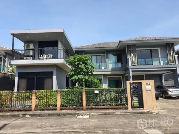 Detached House for sale in Suan Luang, Bangkok - Front elevation of a contemporary home featuring a large upper terrace, trimmed hedges and driveway parking.