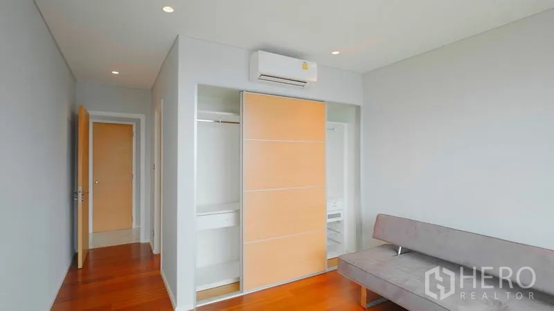 คอนโด ขาย - ห้องนอนพร้อมตู้เสื้อผ้าบานเลื่อน เครื่องปรับอากาศผนัง และพื้นไม้โทนอุ่น