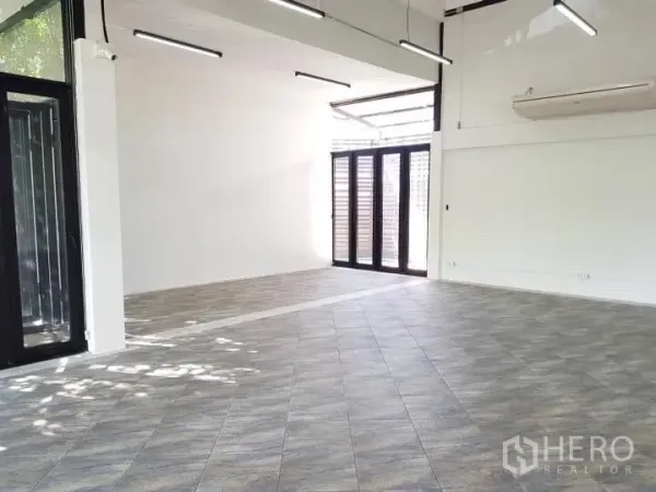 办公空间 出租在Chatuchak, Bangkok - 角落工作区，配折叠玻璃门、高挑天花和瓷砖地面。