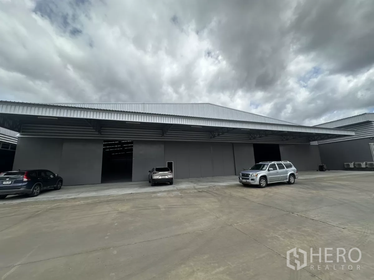 Warehouse for rent in Khlong Toei, Bangkok - Modern grey warehouse exterior with wide covered loading bays and a large concrete yard.