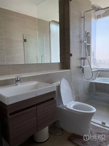 Condominium for rent in Bang Kho Laem, Bangkok - Contemporary bathroom with vanity, toilet, and glass-enclosed tub.