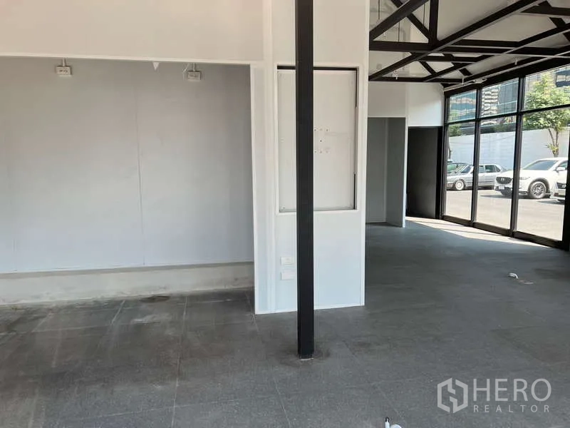 พื้นที่ขายปลีก ให้เช่า - โซนขายกว้าง ผนังสีขาว เสาภายในสีดำ และพื้นกระเบื้องสีเทา.