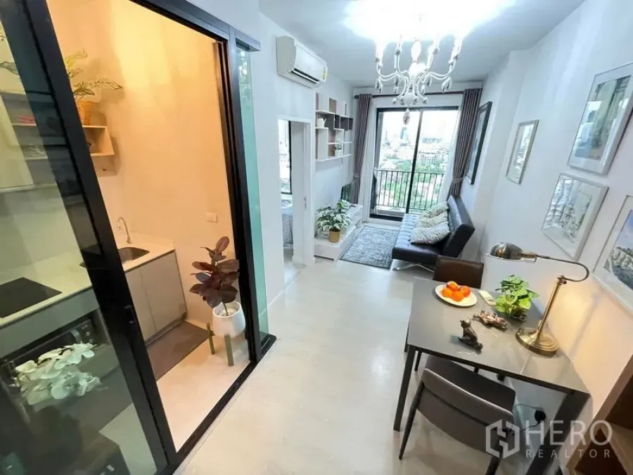 Condominium for sale in Huai Khwang, Bangkok - Open-plan perspective showing kitchenette, dining table and lounge leading to the balcony.