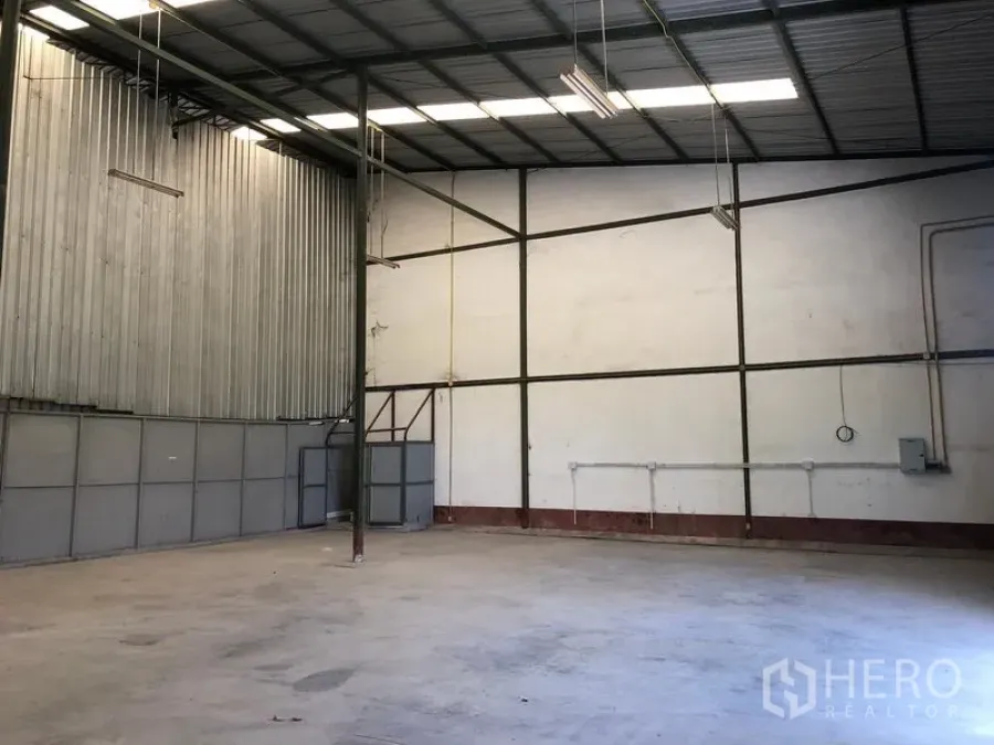 Warehouse for rent in Lat Krabang, Bangkok - High-ceiling warehouse interior in Lat Krabang, Bangkok with steel frame, skylights, concrete floor and visible electrical lines.
