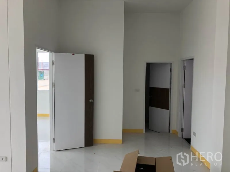 工厂 出租或出售在Sai Noi, Nonthaburi - 明亮的办公室走廊，白墙、多扇门与亮面地砖。