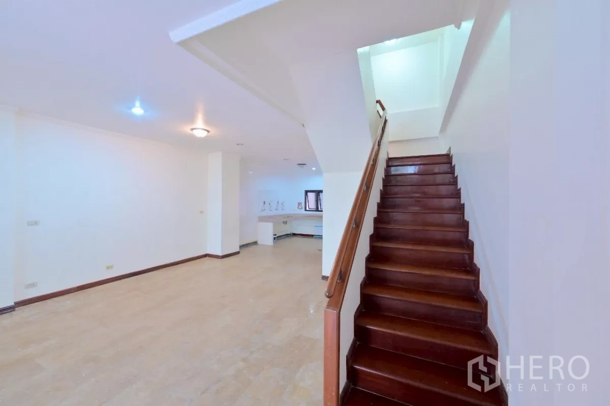 Townhouse for sale in Watthana, Bangkok - Close-up of wooden staircase rising from an open-plan living area.