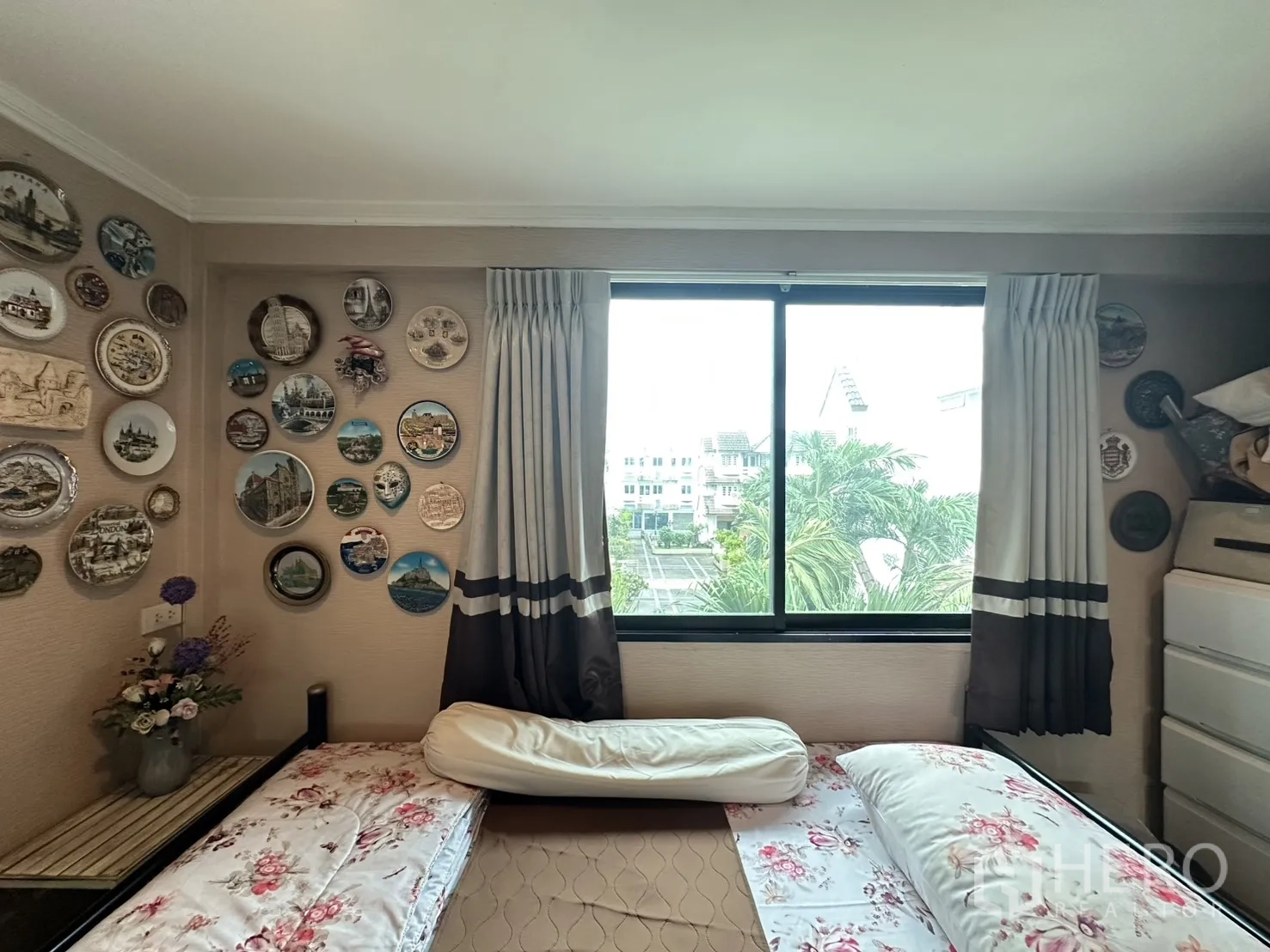 Shophouse for sale in Watthana, Bangkok - Cozy secondary bedroom with decorative plates on the wall and a window view.