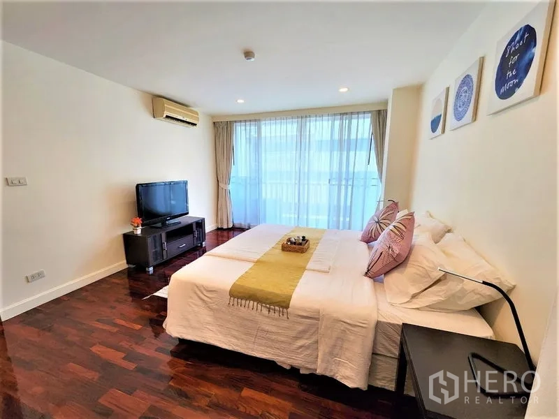 Condominium for rent in Bang Rak, Bangkok - Cozy bedroom with king bed, TV console, air-conditioning and full-height windows.