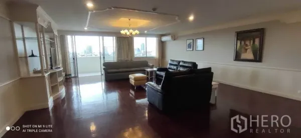 คอนโด ให้เช่าในWatthana, Bangkok - มุมกว้างห้องนั่งเล่นมีโคมระย้า โซฟา และทางออกสู่ระเบียงชมวิวเมือง