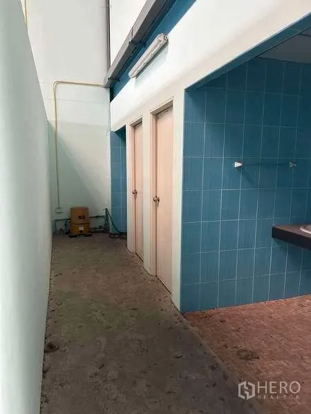 货栈 出租在Bang Phli, Samut Prakan - 仓库卫生间走道，蓝色瓷砖，多间隔门与洗手台。