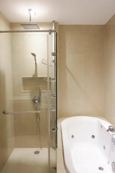 Condominium for rent in Pathum Wan, Bangkok - Bathroom with glass rain shower beside a separate white soaking bathtub.