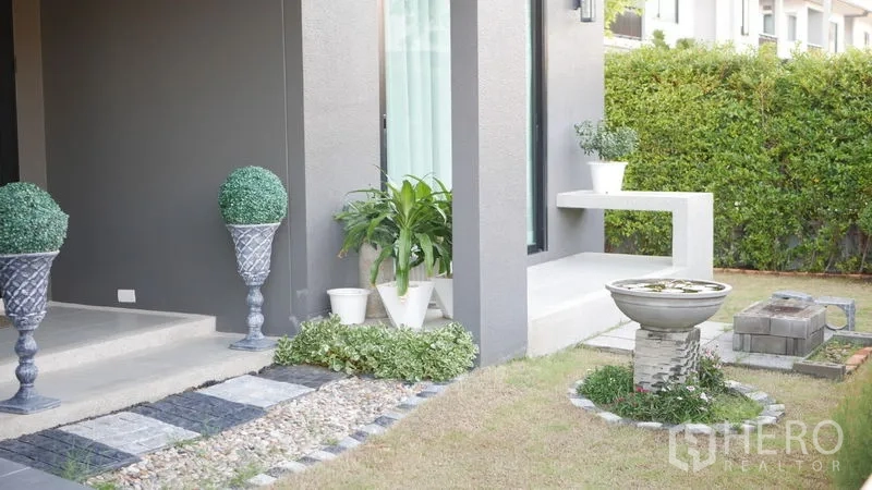 Detached House for rent or sale in Bang Bo, Samut Prakan - Front garden with stone path, planters and a small water feature by the covered porch.