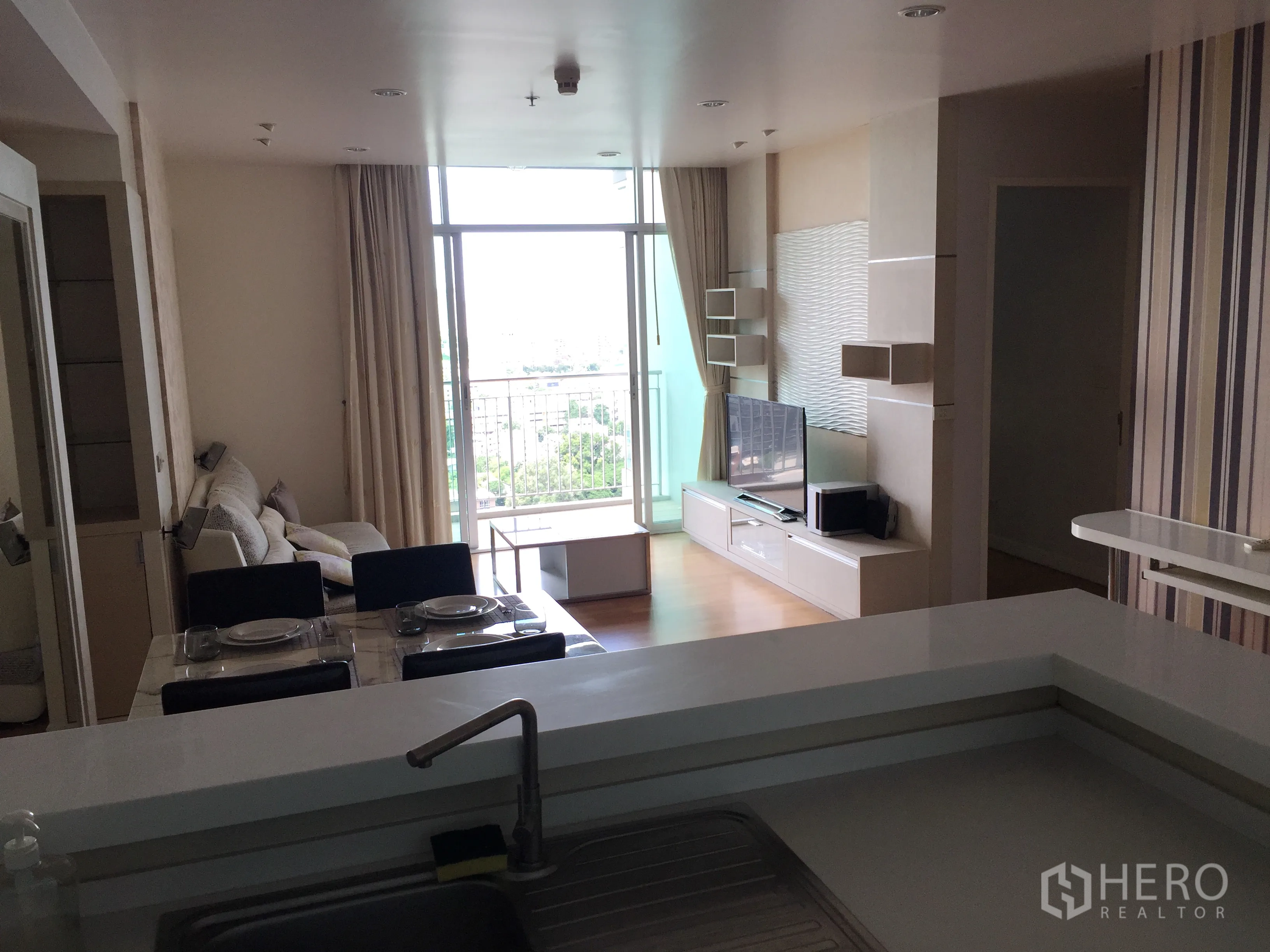 公寓 出租或出售在Sathon, Bangkok - 开放式客餐厅，带电视柜与通往阳台的落地推门，自然采光充足。