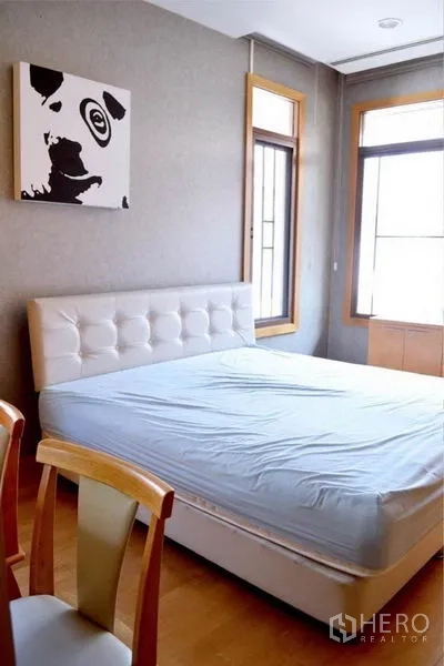 Detached House for rent or sale in Bang Phli, Samut Prakan - Guest bedroom with upholstered bed, corner windows and wood furniture.